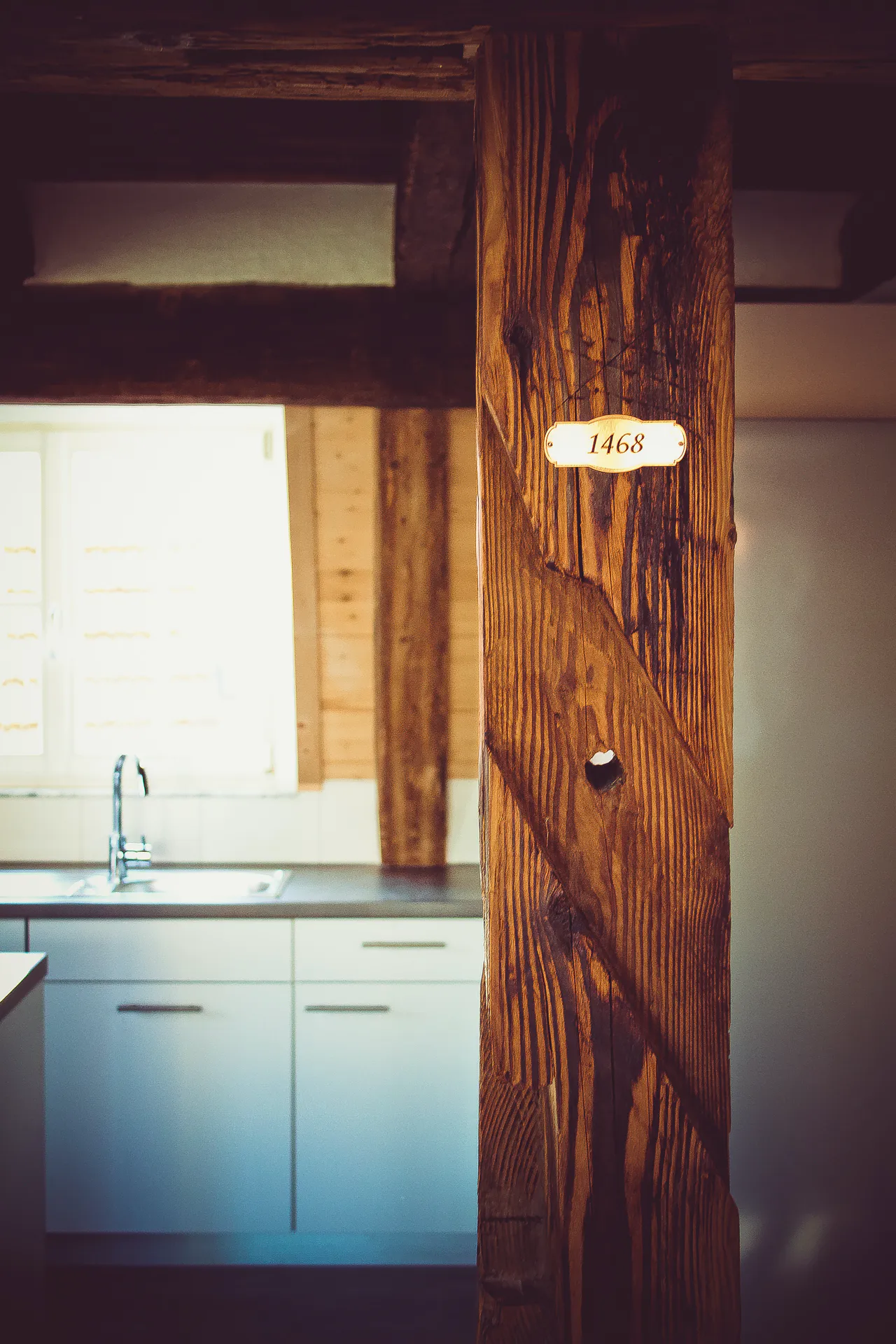 nachhaltige-Sanierung-in-Renningen-Restauriertes-innen-Sichtfachwerk-im-Einfamilienhaus-Lauffer-Holzbau-Zimmerei-Renningen-3 Nachhaltige Sanierung in Renningen: Plakette auf einem Holztragpfeiler in einer Küche zeigt das Jahr 1468. Restauriertes Stockwerk mit innerem Sichtfachwerk, saniert und restauriert von der Firma Lauffer Holzbau-Zimmerei in Renningen.