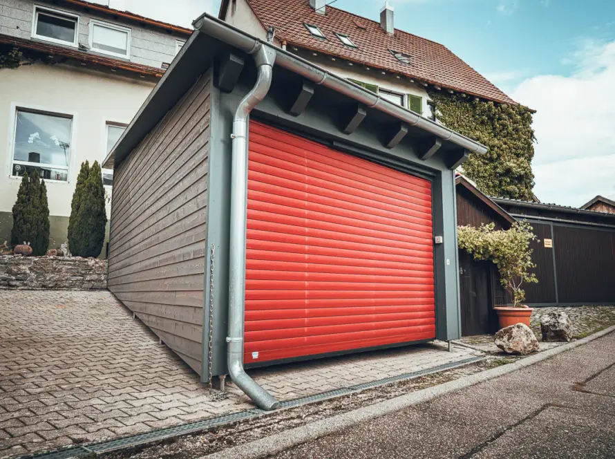 Lauffers klassisches Bauprojekt: moderner Carport in Holzverschalung mit Stützfüßen für den konstruktiven Holzschutz.