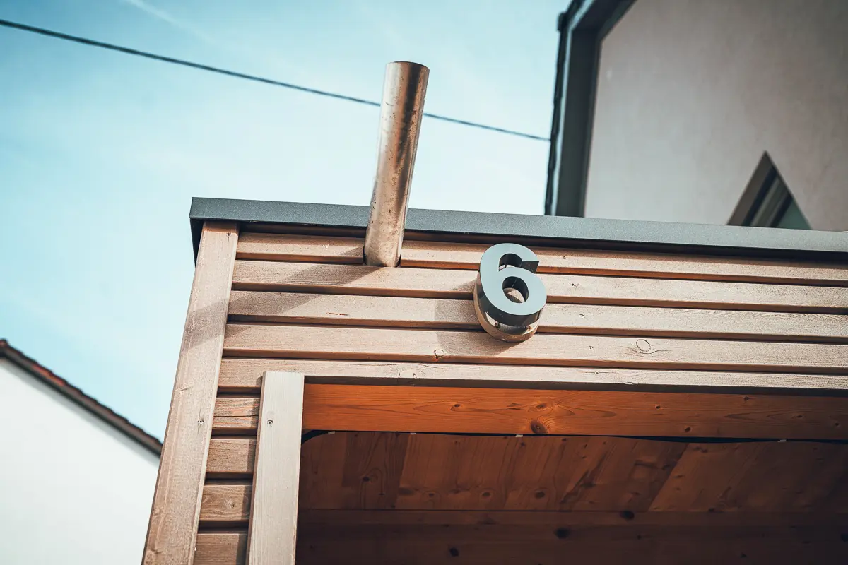 Lauffers Bauprojekt: Carport in sichtbarer Holzverschalung an einem Einfamilienhaus mit Entwässerungsdetail.