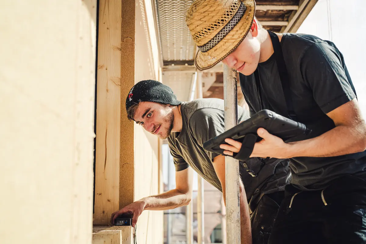 Zwei Mitarbeiter des Teams von Lauffer Holzbau-Zimmerei beim Aufmaß einer neuer Fassadendämmung an einem Einfamilienhaus in Renningen.