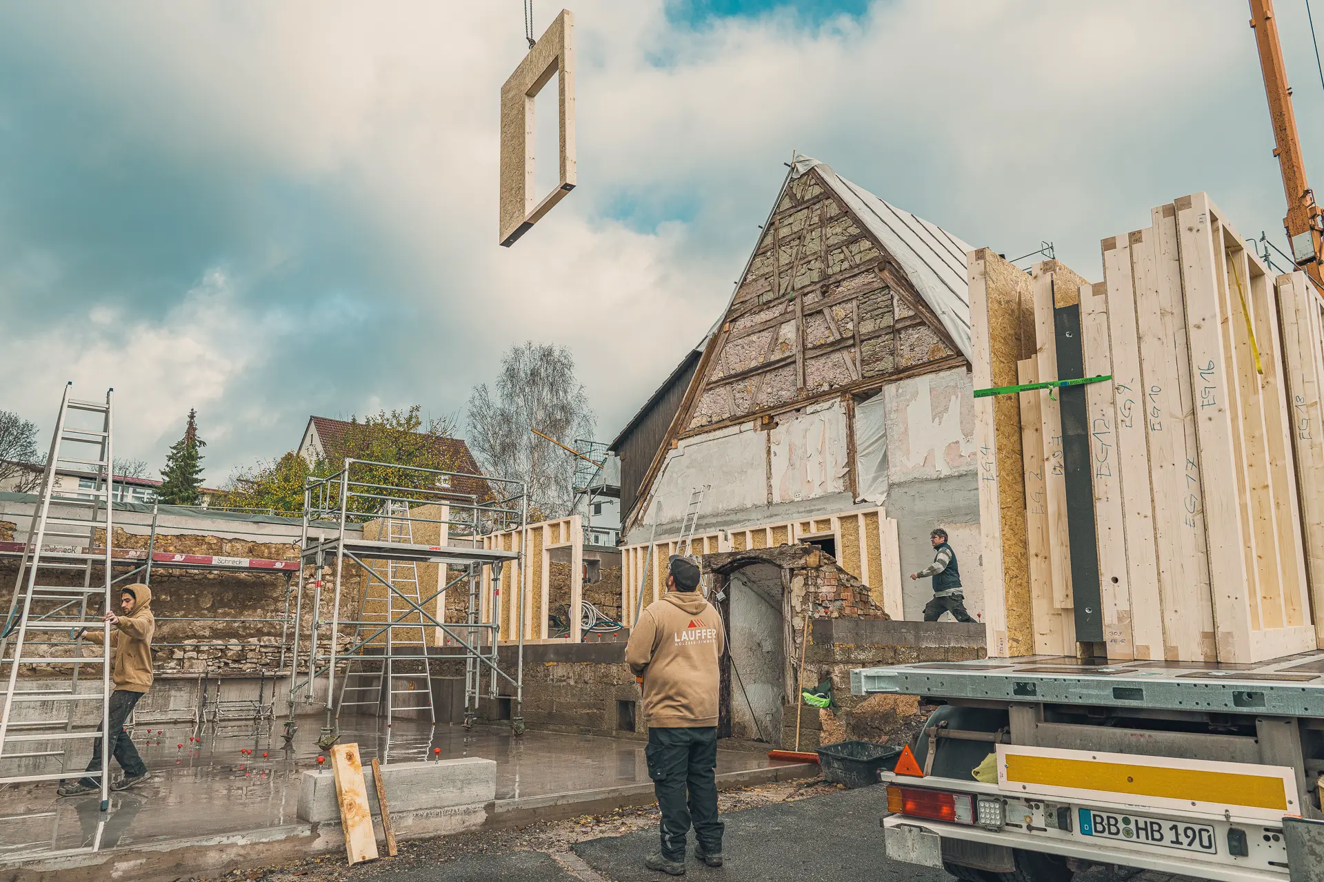 Der Inhaber von Lauffer Holzbau-Zimmerei, Steffen Lauffer, lenkt den Kran, der eine Holzrahmenwand platziert für den Bau eines Mehrfamilienhauses in Renningen-Malmsheim.