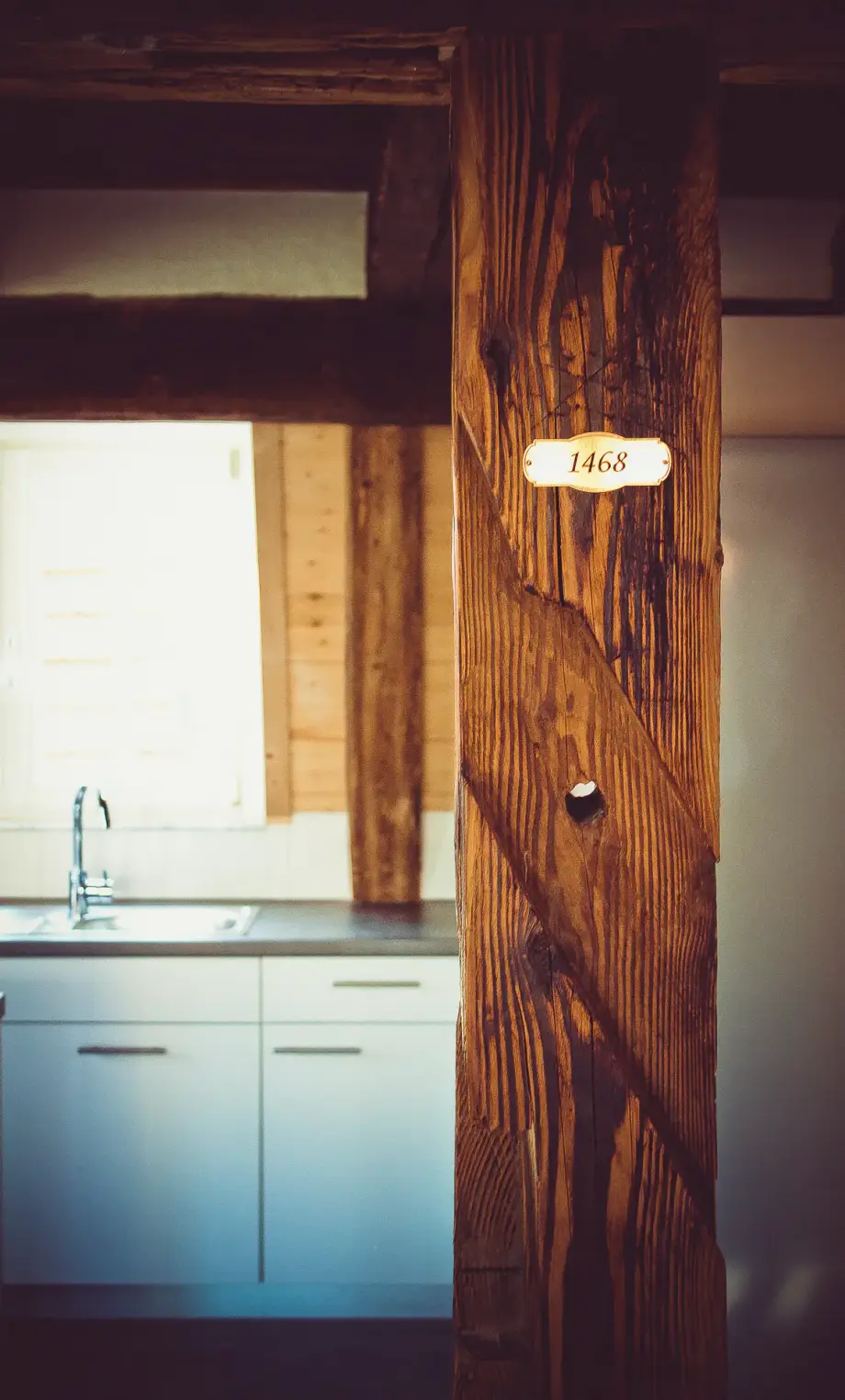 Nachhaltige Sanierung in Renningen: Plakette auf einem Holztragpfeiler in einer Küche zeigt das Jahr 1468. Restauriertes Stockwerk mit innerem Sichtfachwerk, saniert und restauriert von der Firma Lauffer Holzbau-Zimmerei in Renningen.